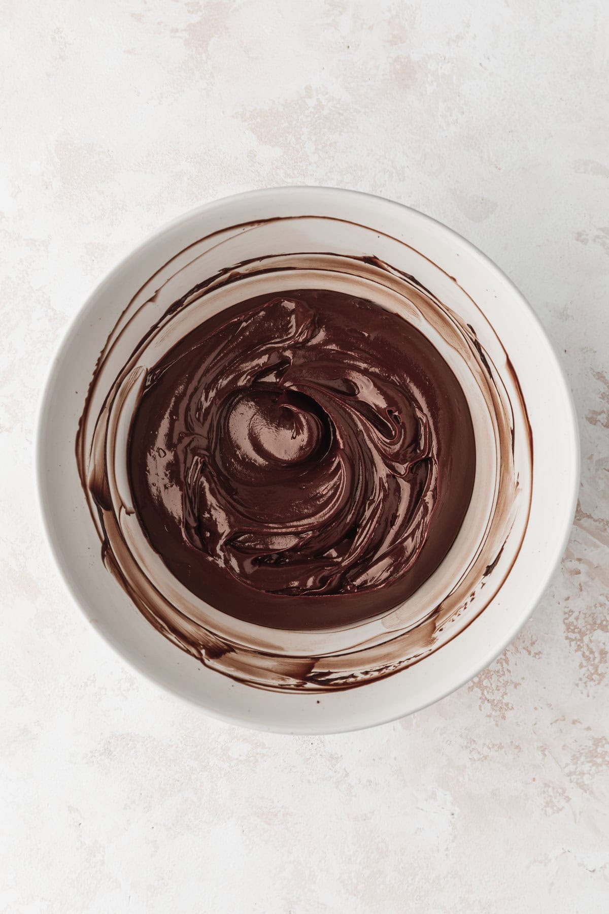 A white bowl of ganache on a white counter.