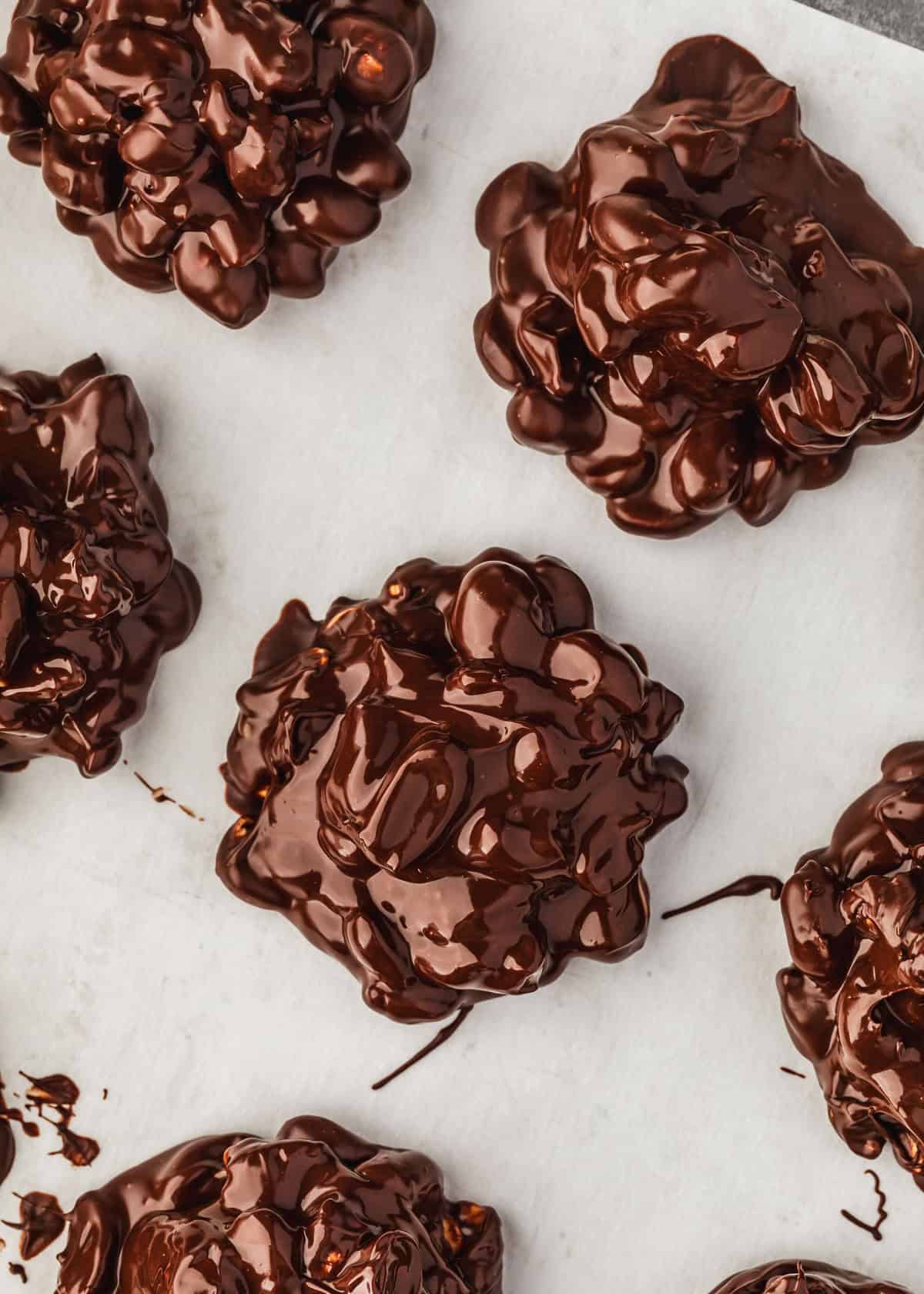 Rows of peanut chocolate clusters on parchment paper.