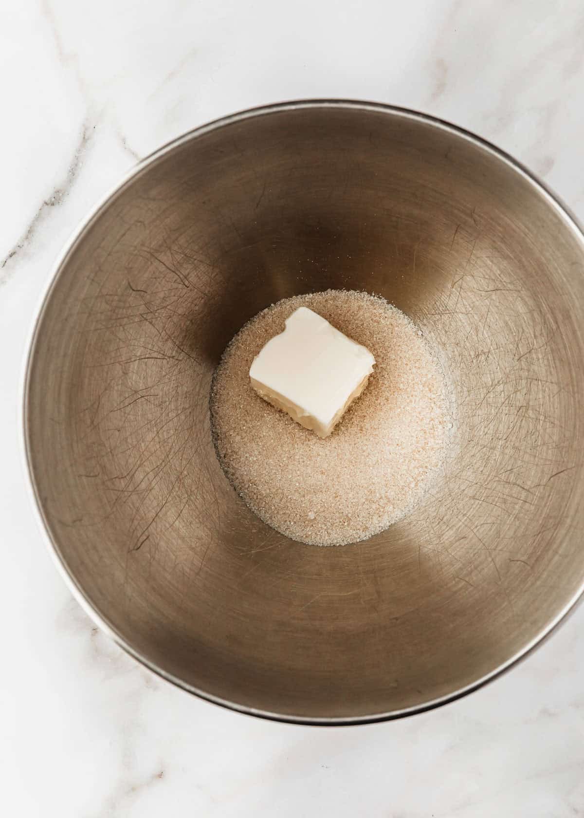 A silver bowl of sugar and butter on a marble counter.