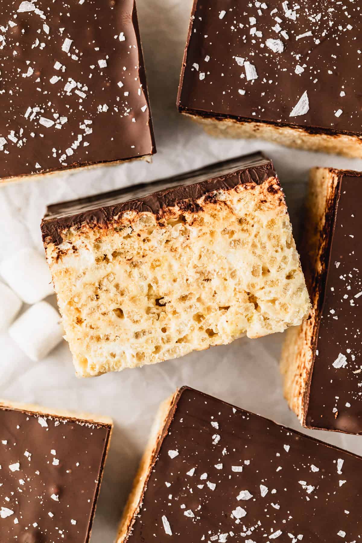 Rows of small batch chocolate covered rice crispy treats on parchment paper.