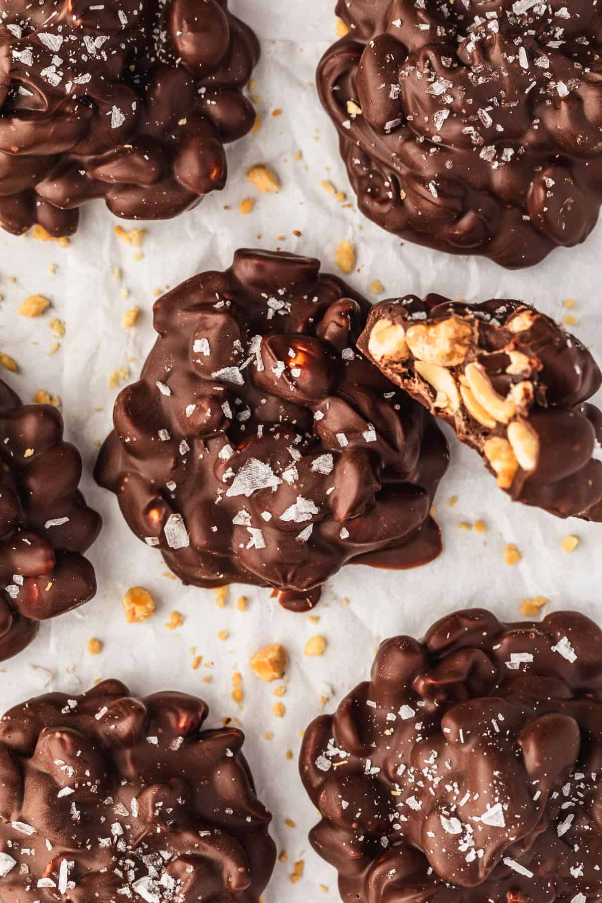 Rows of chocolate peanut clusters on parchment paper.