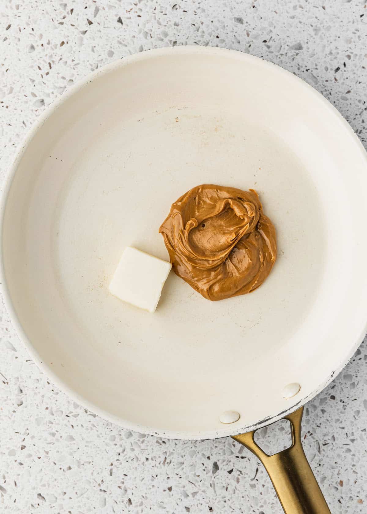 A white pan of butter and peanut butter on a white counter.
