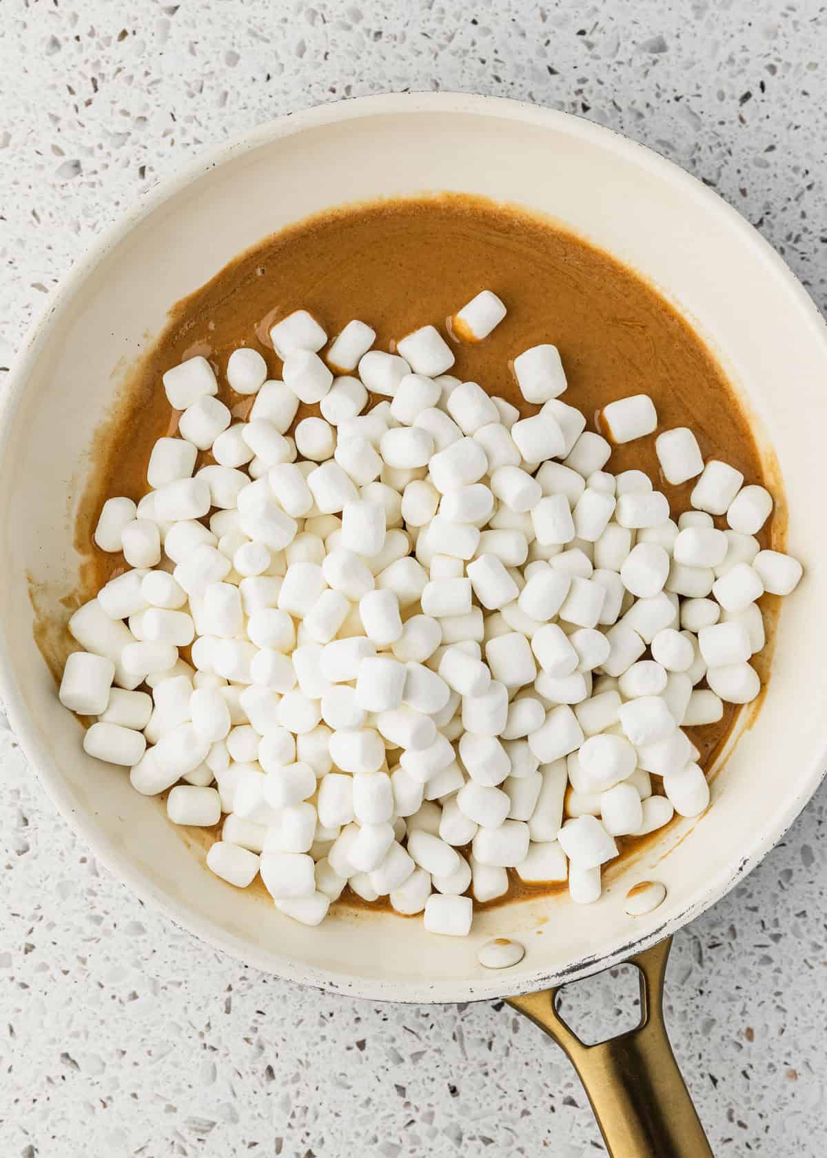 A white pan of marshmallows and peanut butter on a white counter.