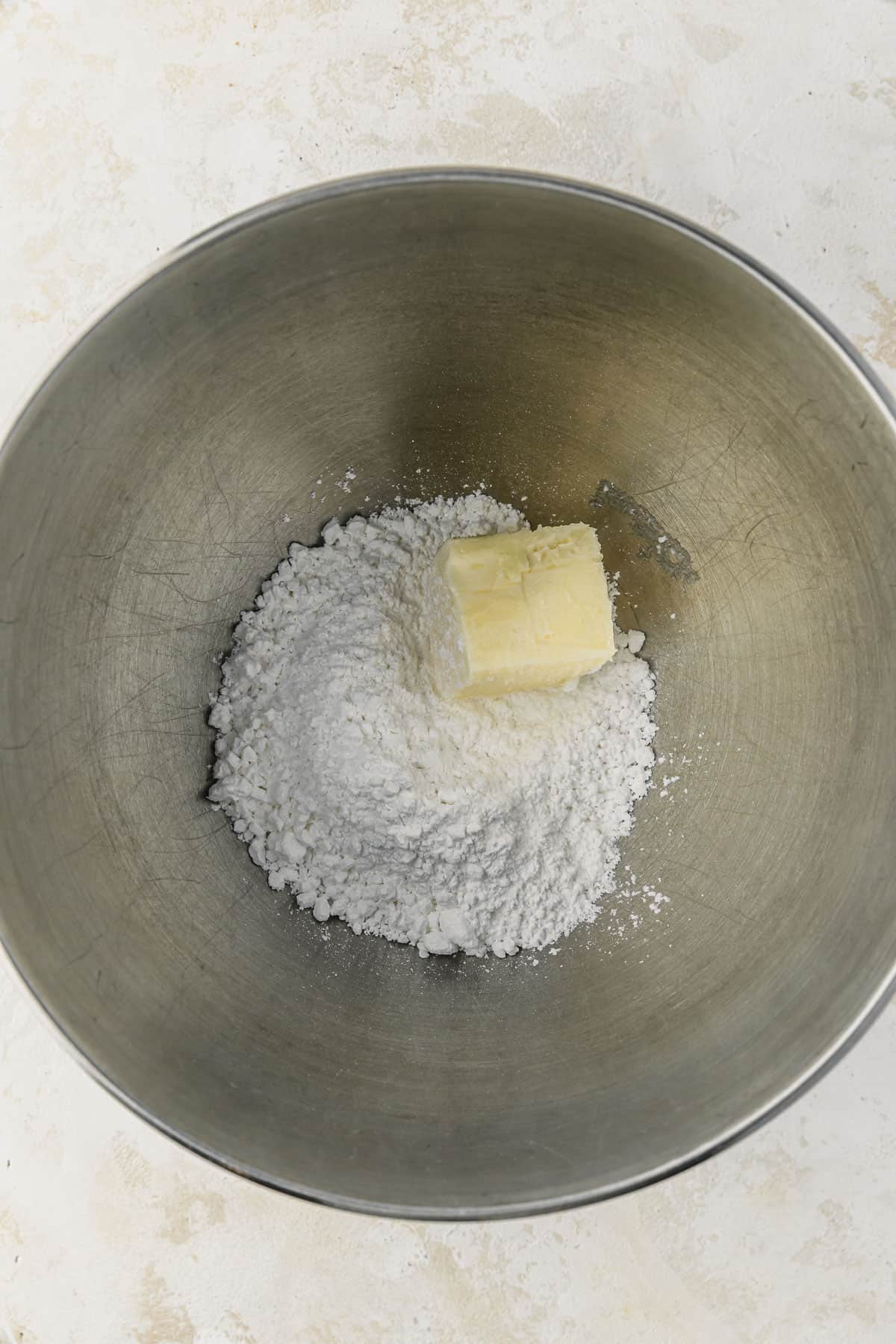 A silver bowl of butter and powdered sugar on a white counter.