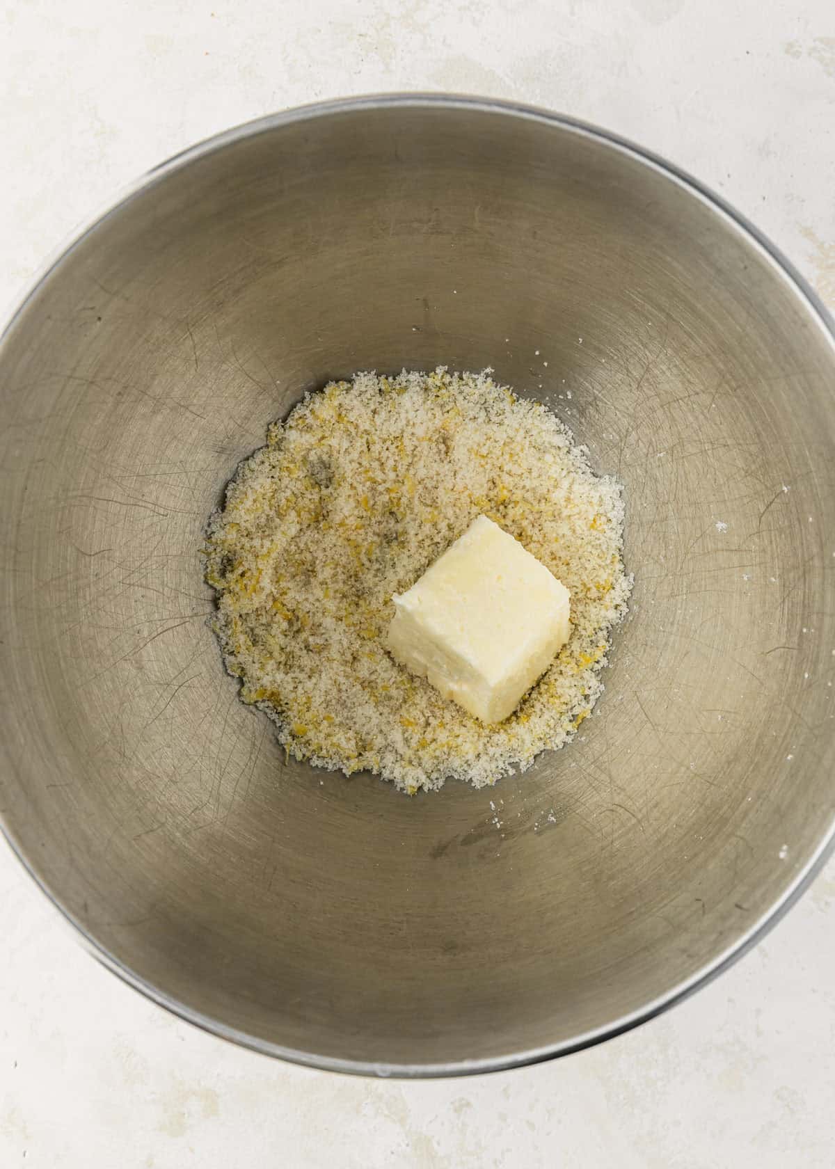 A silver bowl of butter and lemon sugar on a tan counter.