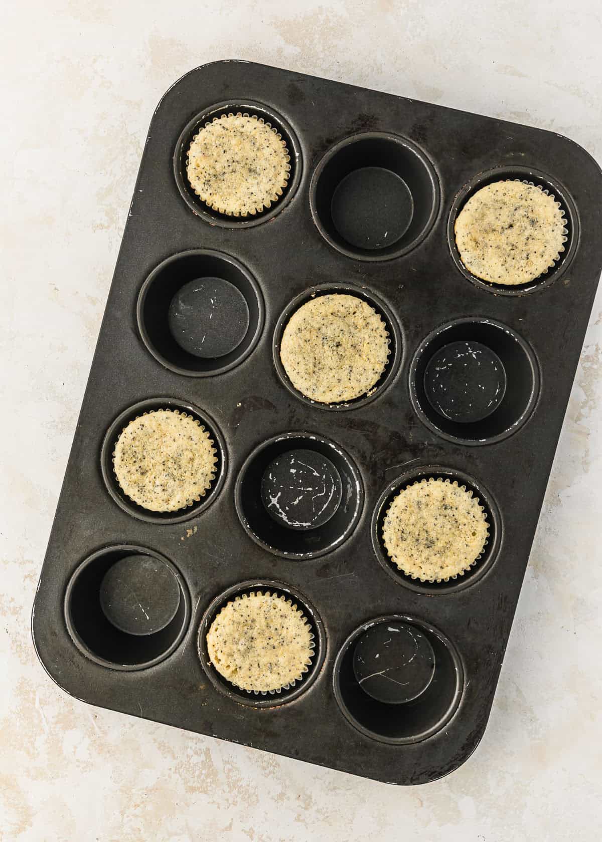 A pan of small batch lemon poppy seed cupcakes on a beige counter.