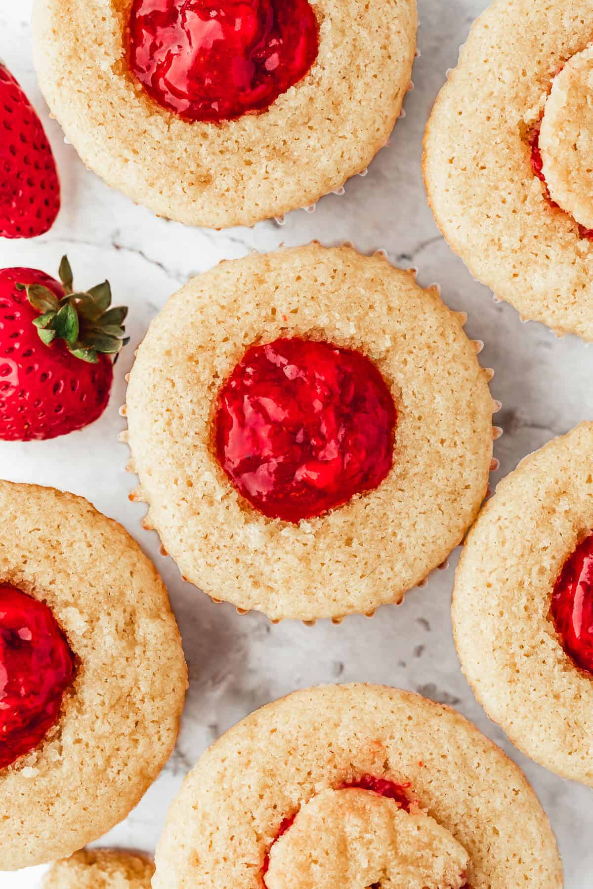 Rows of cupcakes with red jam in the center.