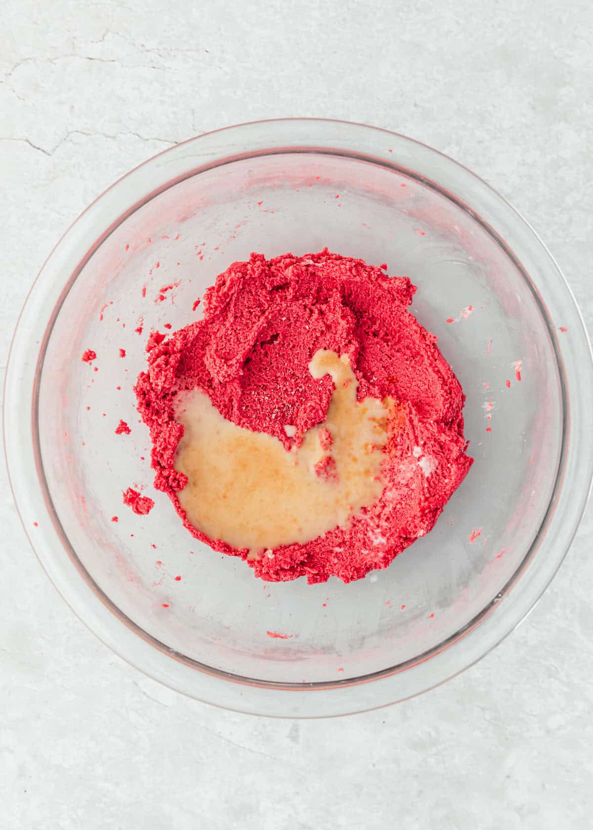 Mixed butter, powdered sugar, and strawberry powder topped with milk and vanilla on a marble counter.