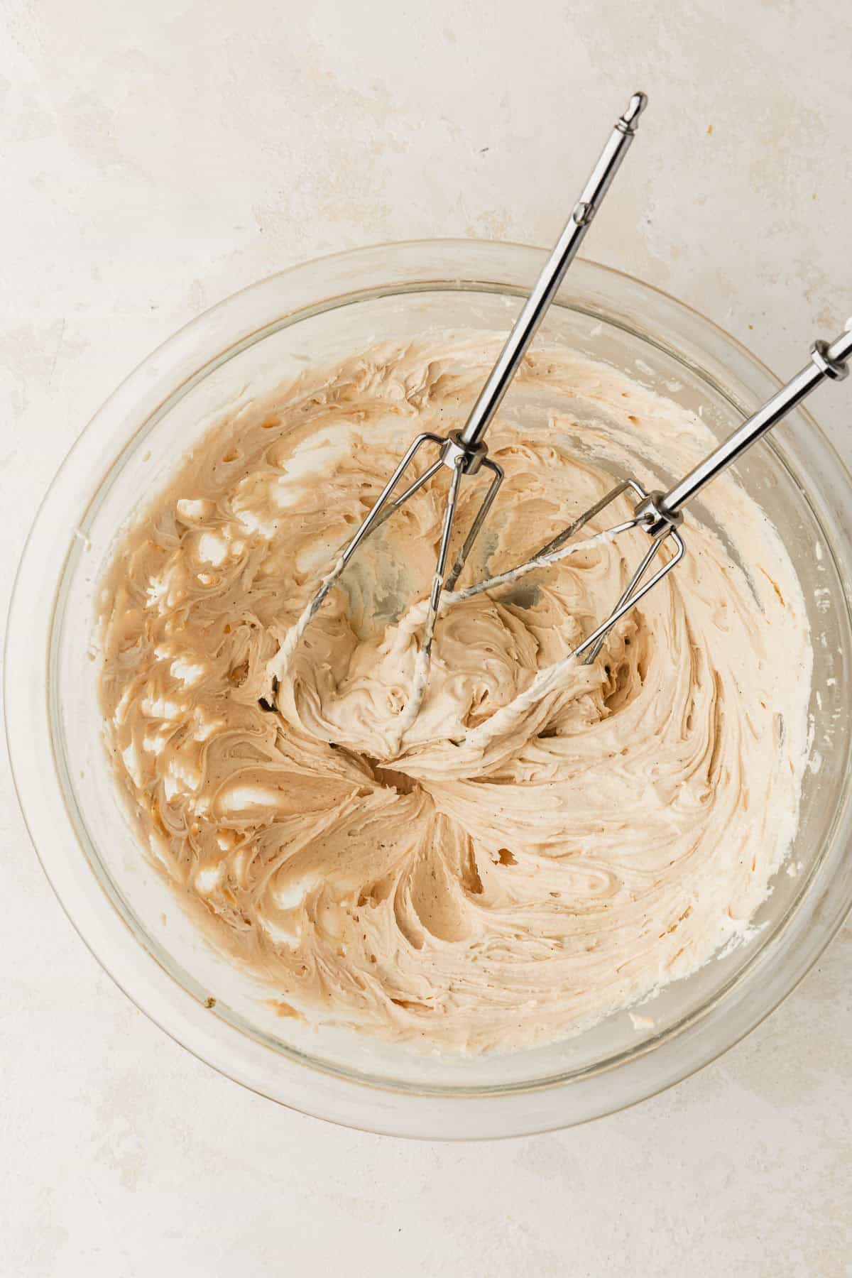 A clear bowl of small batch salted caramel buttercream on a beige counter.