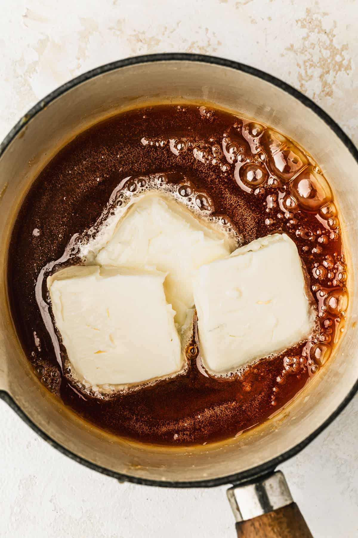 A white pot of small batch caramel sauce and butter.