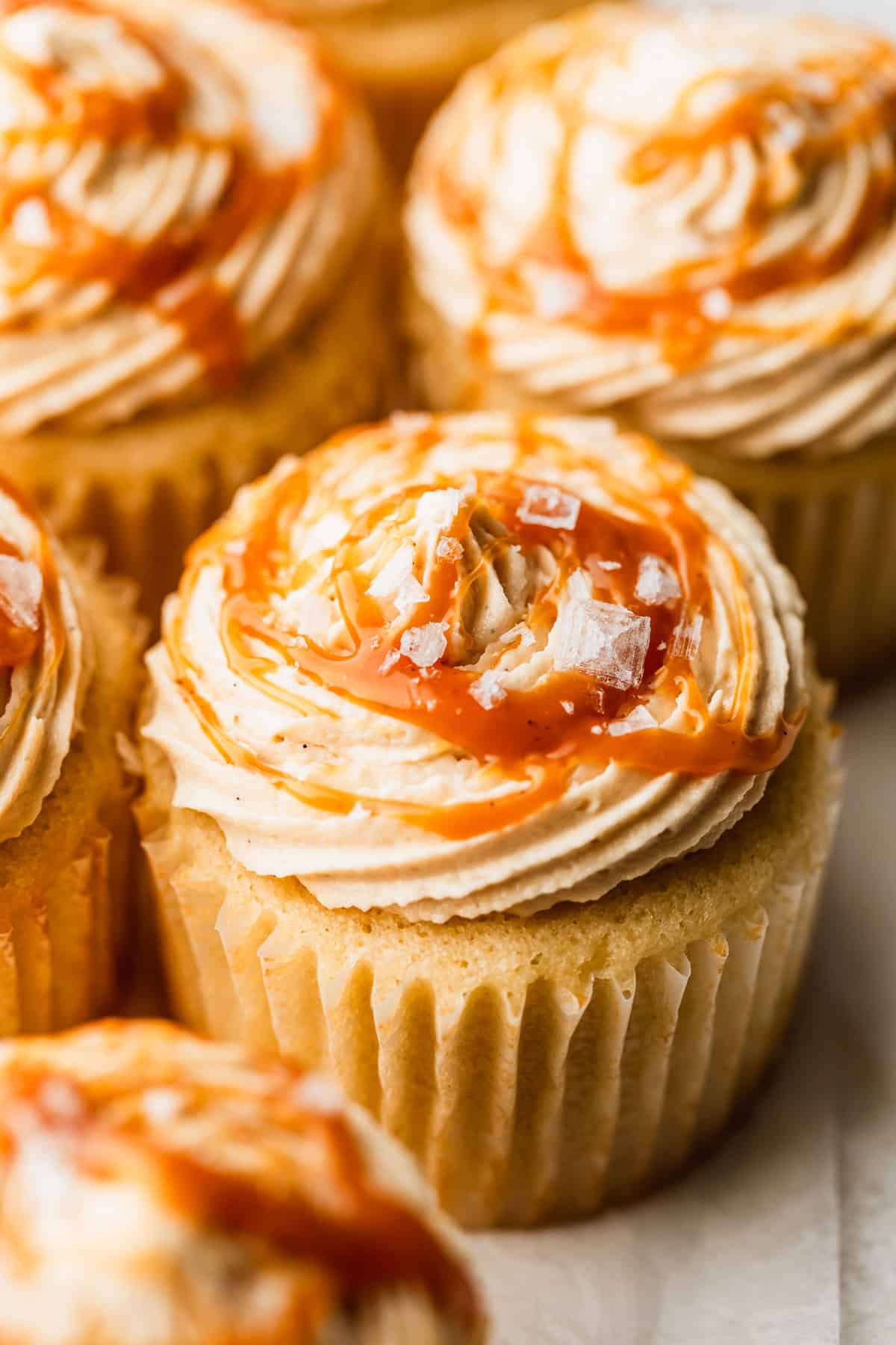 Rows of small batch caramel-filled cupcakes on parchment paper.