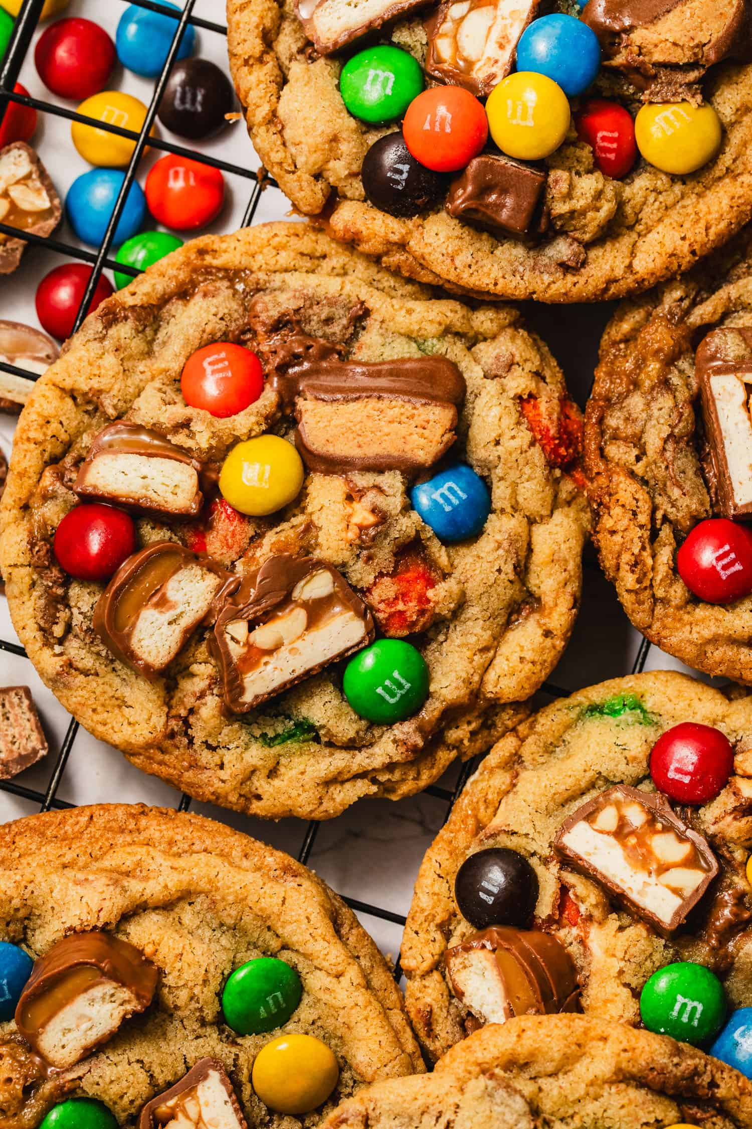 A pile of small batch leftover Halloween candy cookies on a black wire rack.
