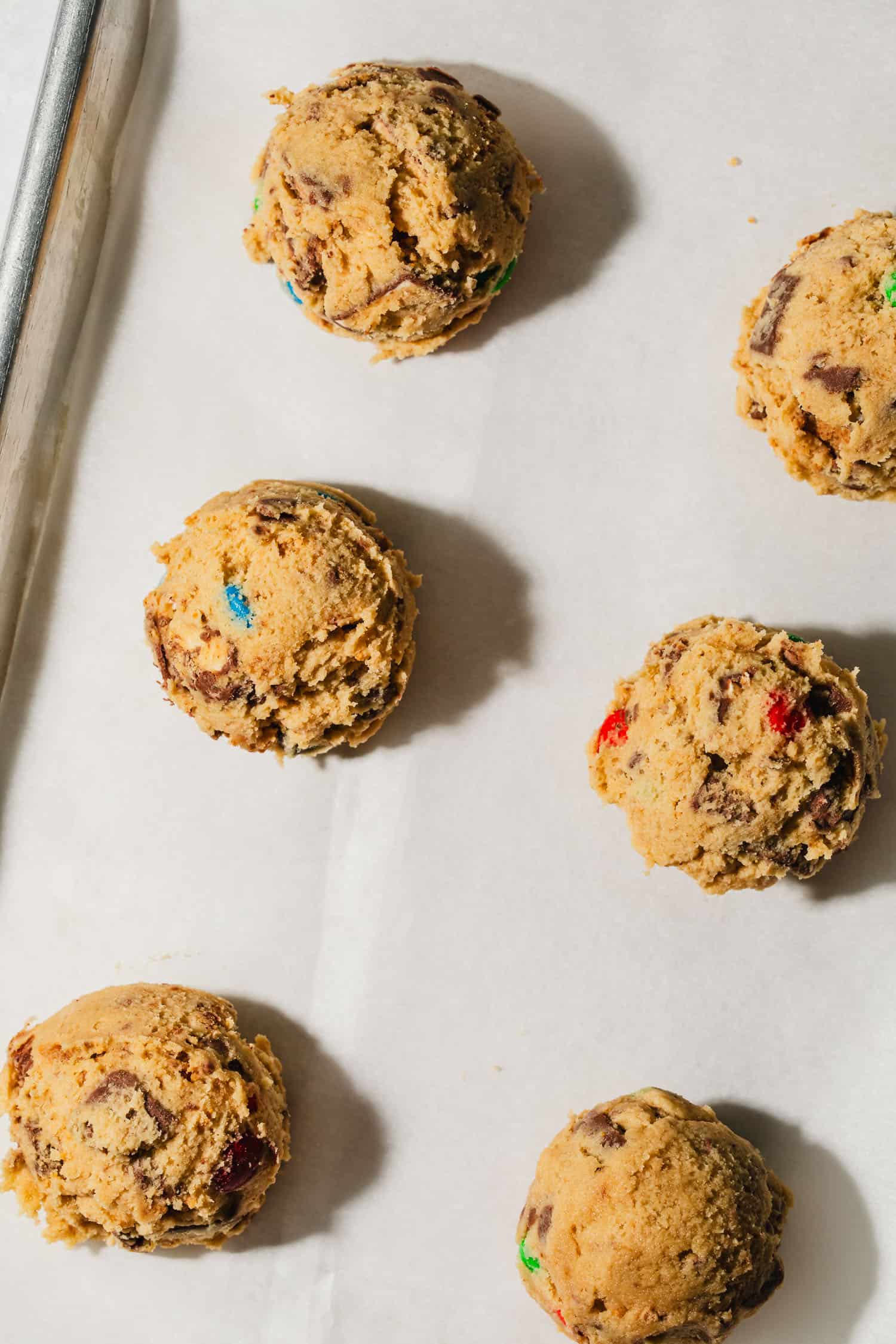 Parchment paper with balls of dough for small batch leftover Halloween candy cookies.