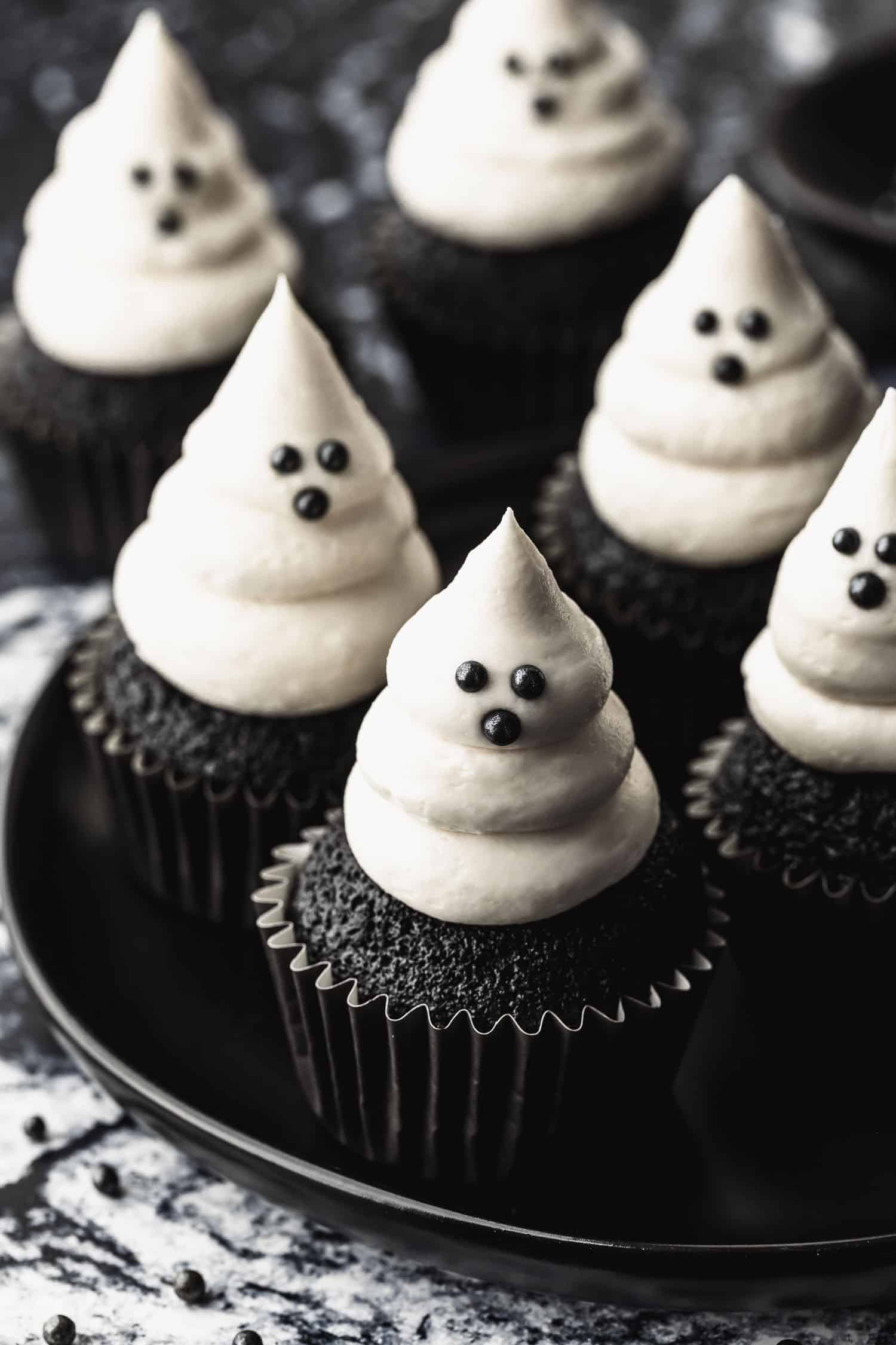 A black plate of small batch ghost cupcakes on a black and white marble counter.