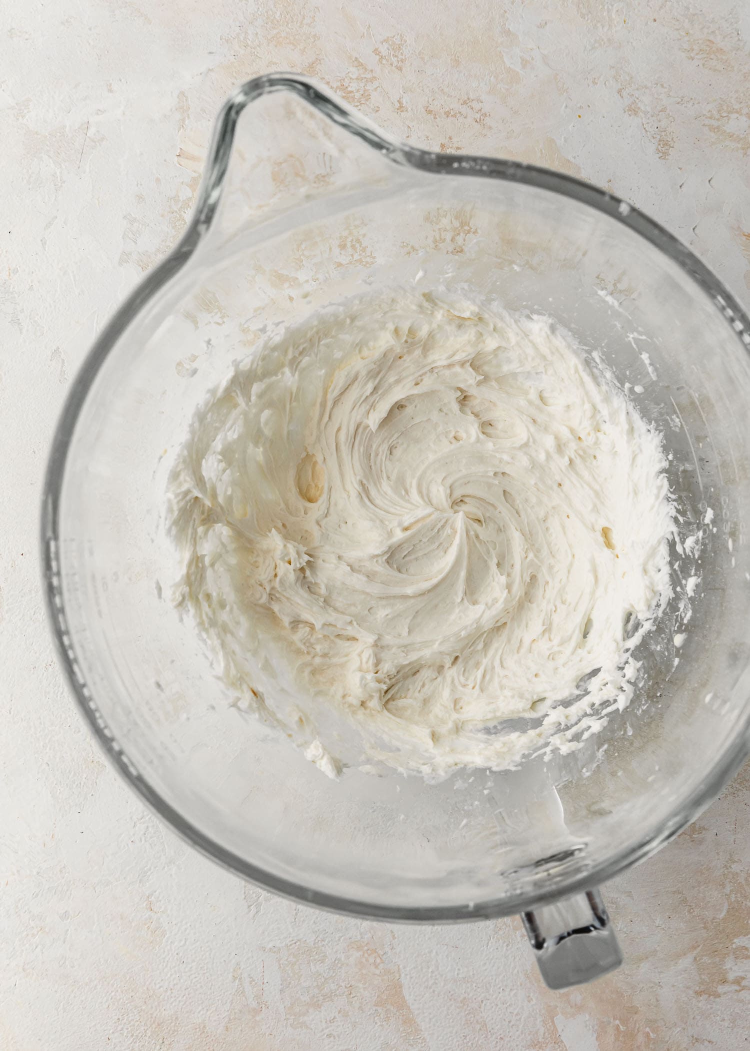 A clear bowl of marshmallow buttercream for small batch ghost cupcakes.