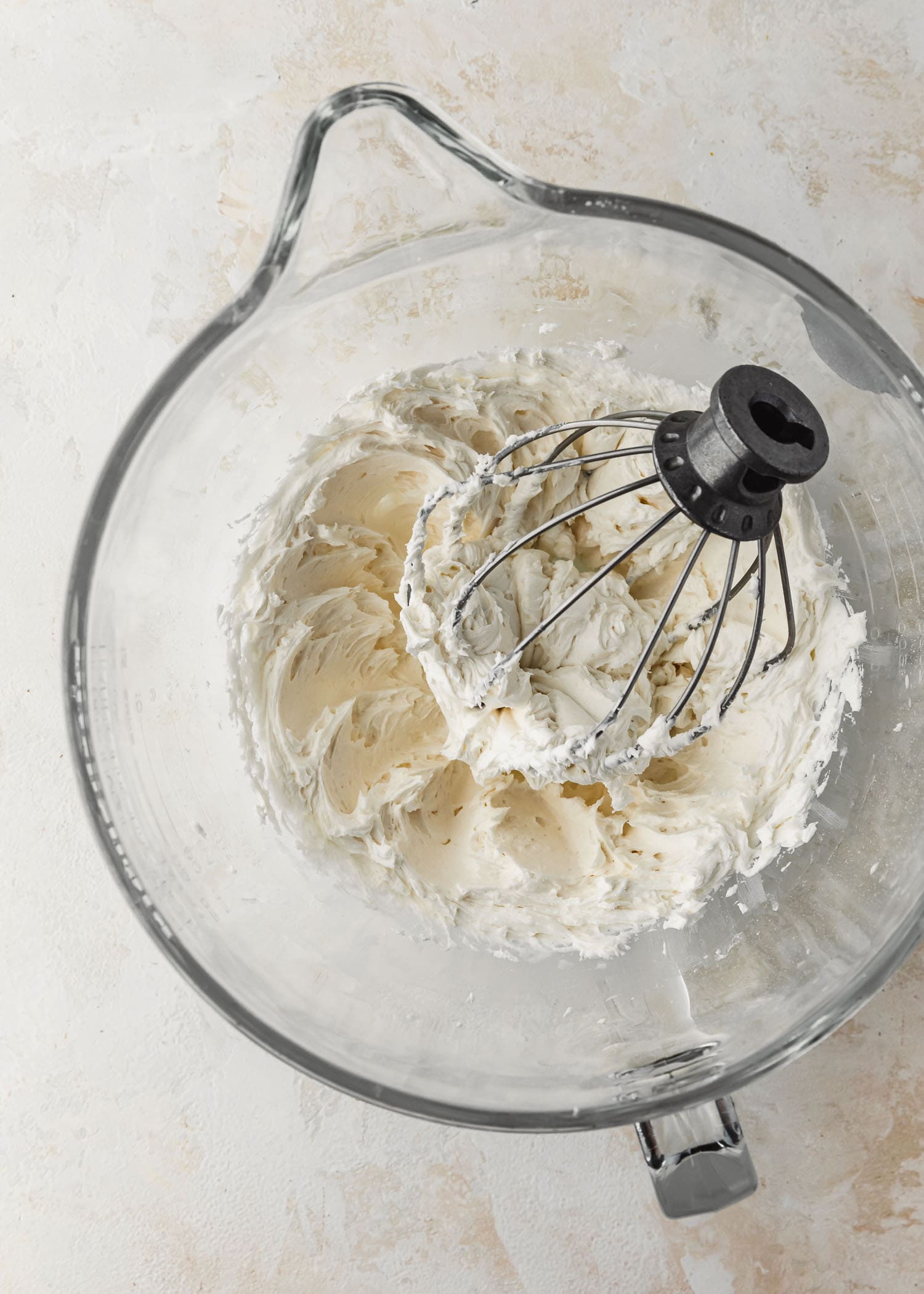 A clear bowl of whipped white frosting for small batch ghost cupcakes.