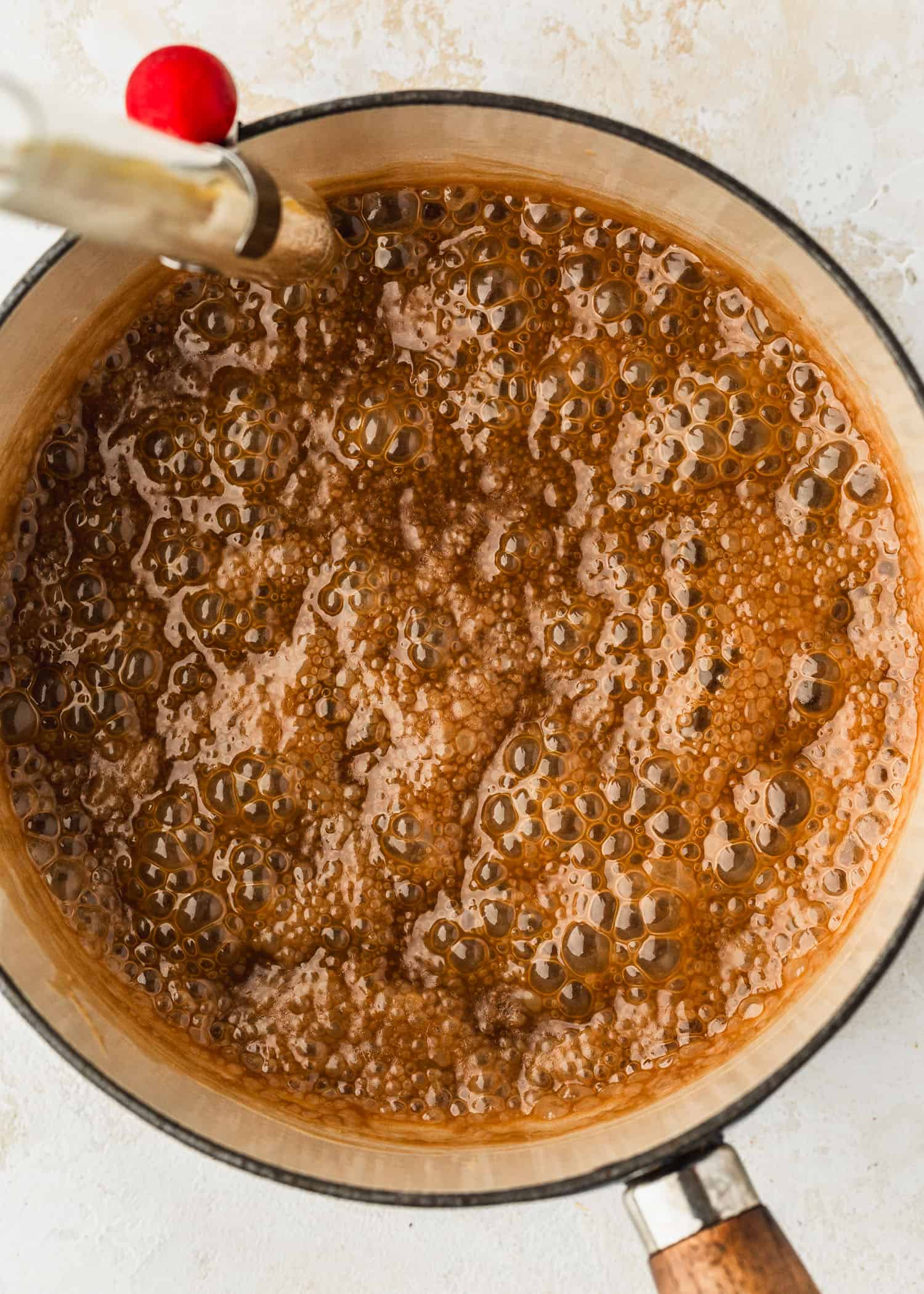 Brown sugar, butter, and cream boiling in a white pot.