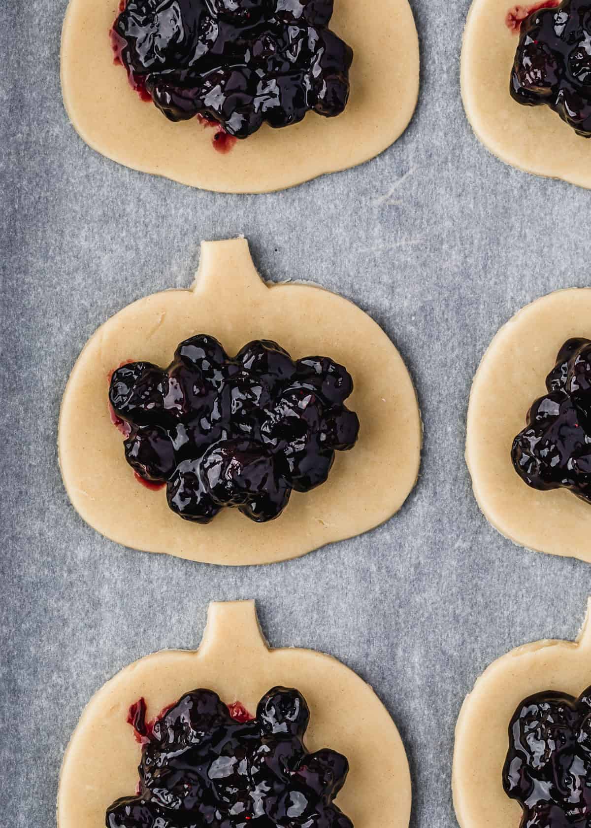 Pieces of pumpkin-shaped pie dough topped with blueberry filling.