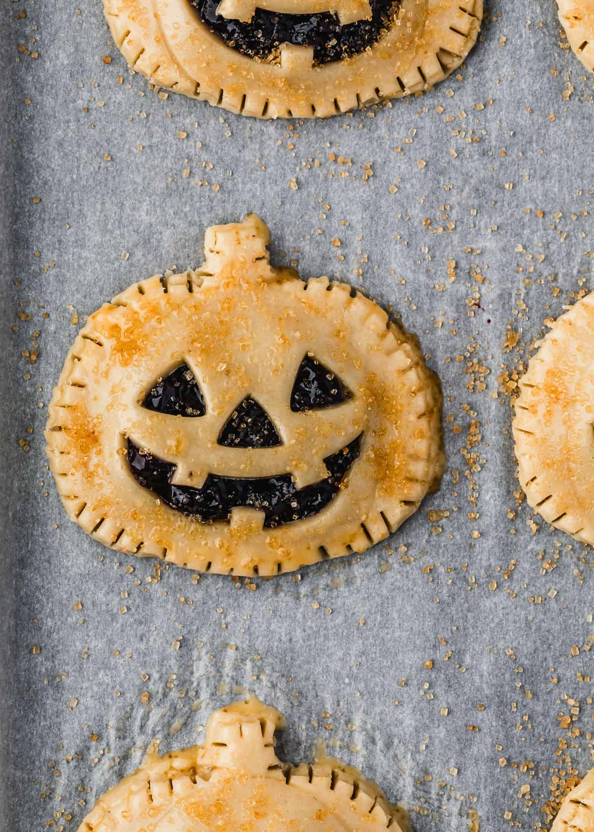 Raw Jack o'lantern hand pies topped with raw sugar.