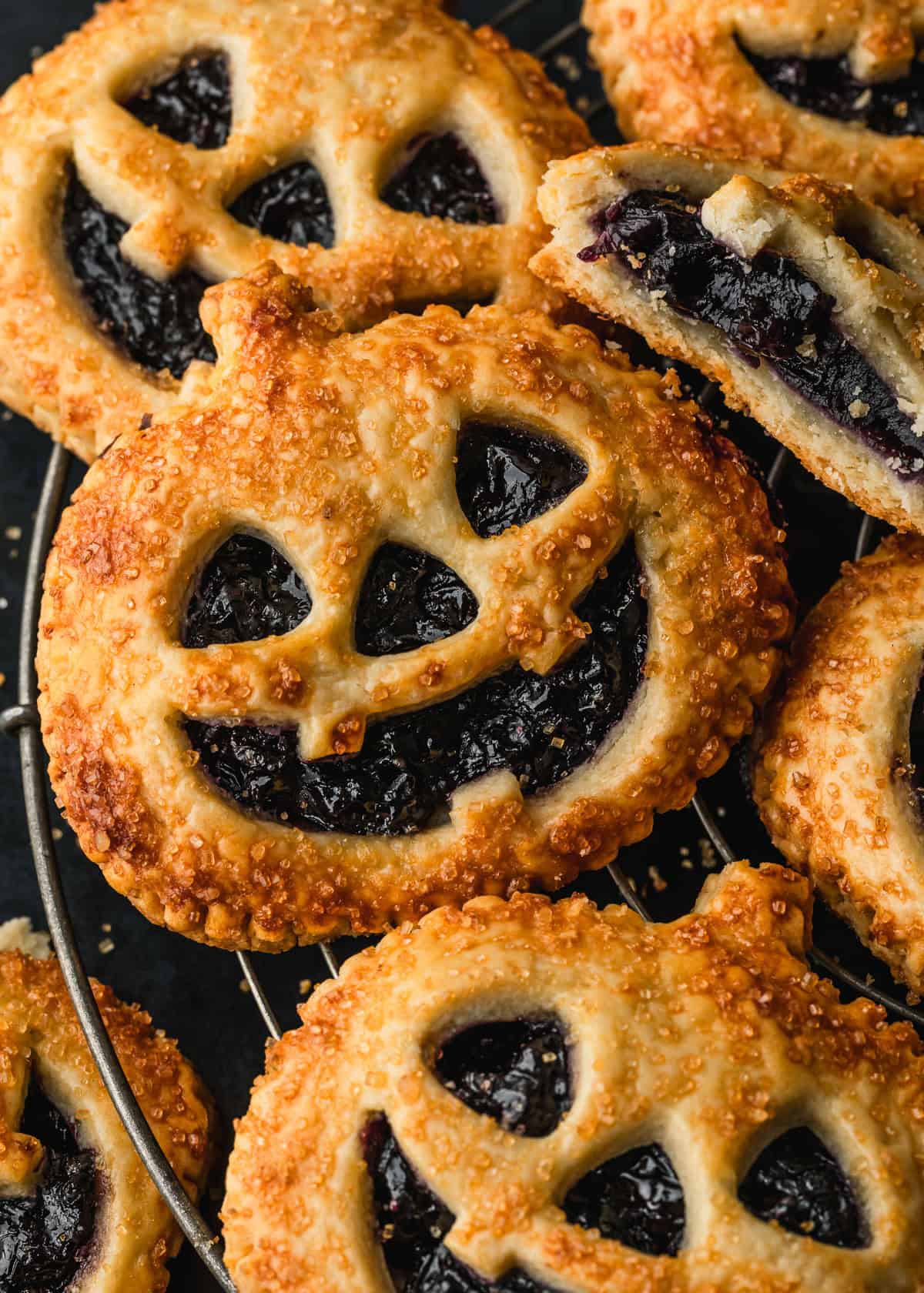 Rows of Jack o'lantern hand pies on a wire rack.