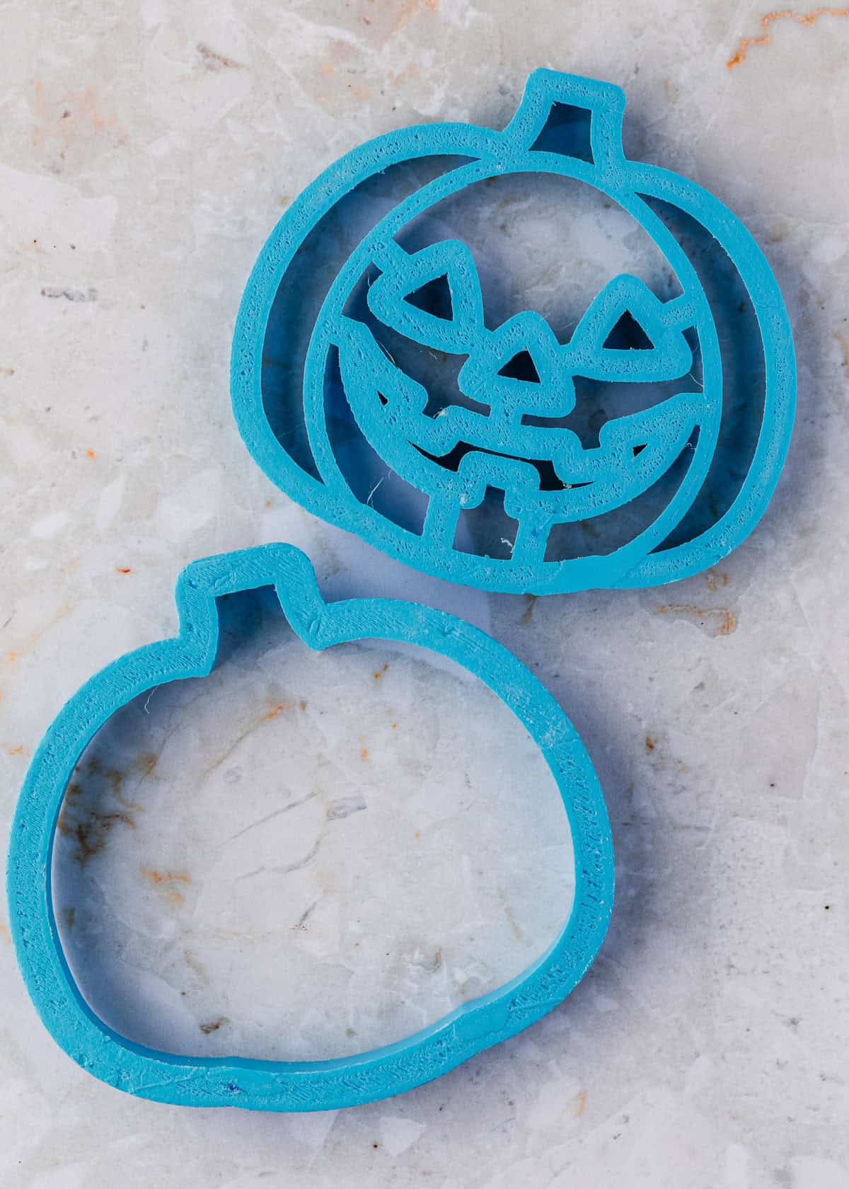 A pumpkin cookie cutter on a white counter.