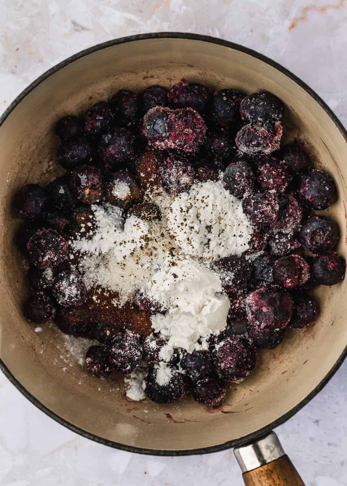 A white pot of blueberries topped with cornstarch and sugar.