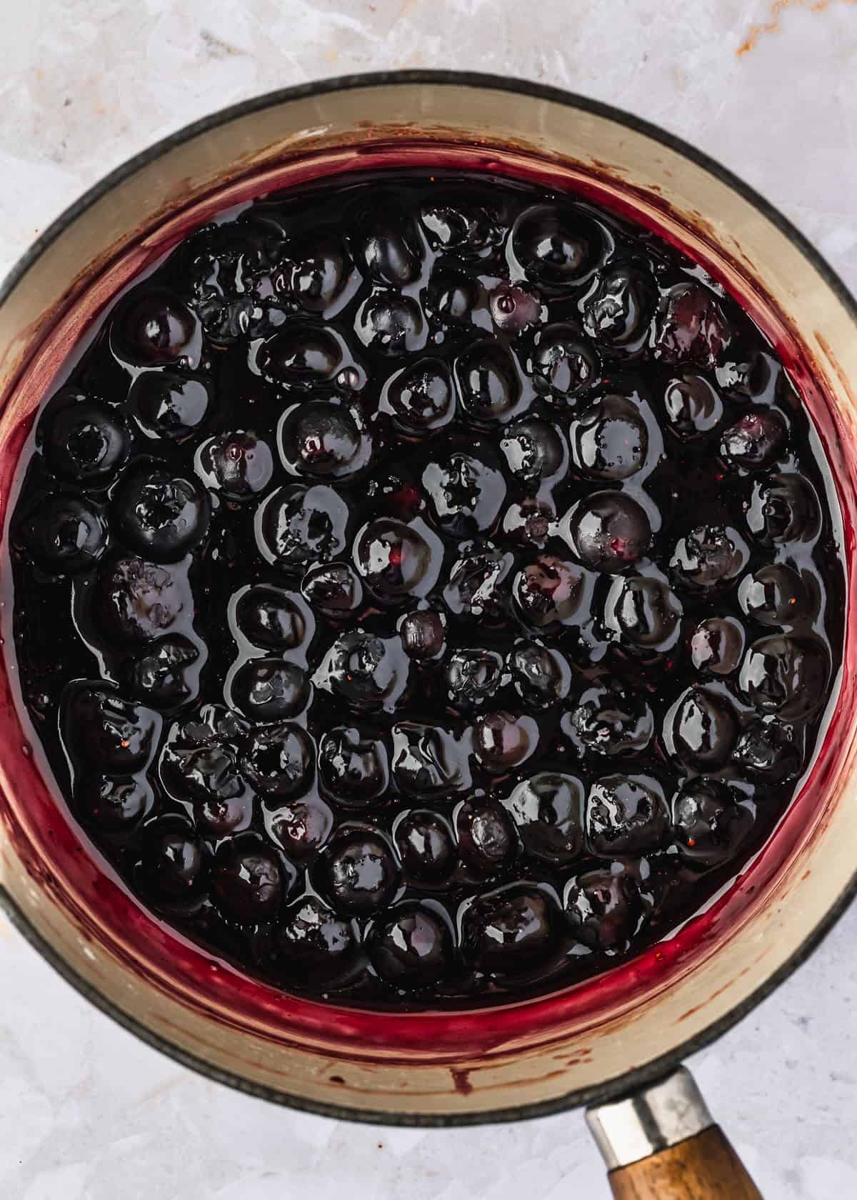 A white pot of blueberry pie filling on a white stone counter.