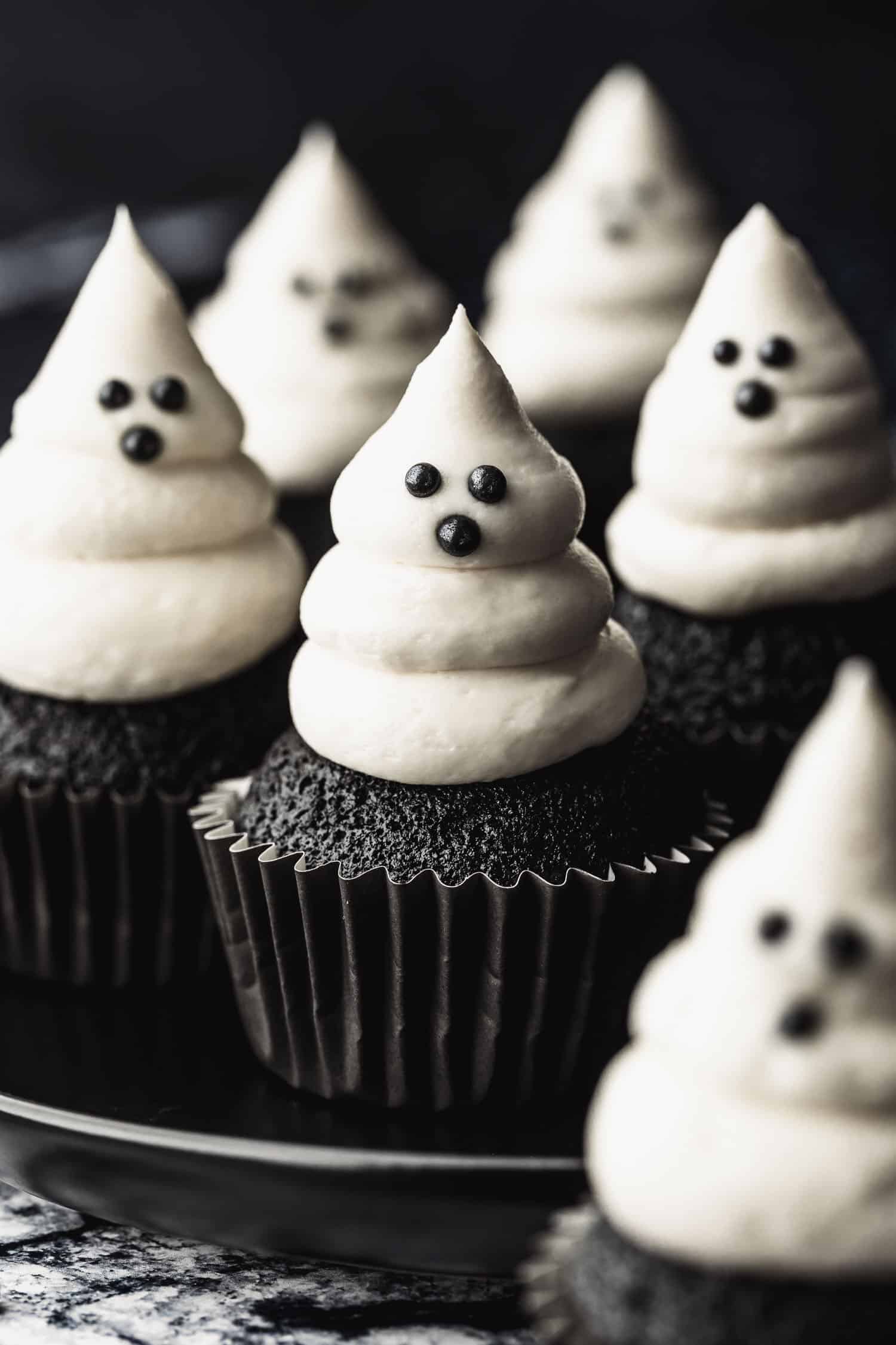 A black plate of small batch ghost cupcakes on a black and white stone counter.